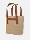 Jute T-Strap Tote with durable vegan leather handles and back strap for easy luggage attachment, perfect for travel.