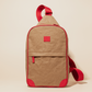 Compact tan sling bag with red straps and accents, designed for easy adjustment and secure, hands-free carry.