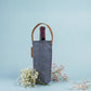 Wine bottle in a navy tote with a sahara handle on a light blue background