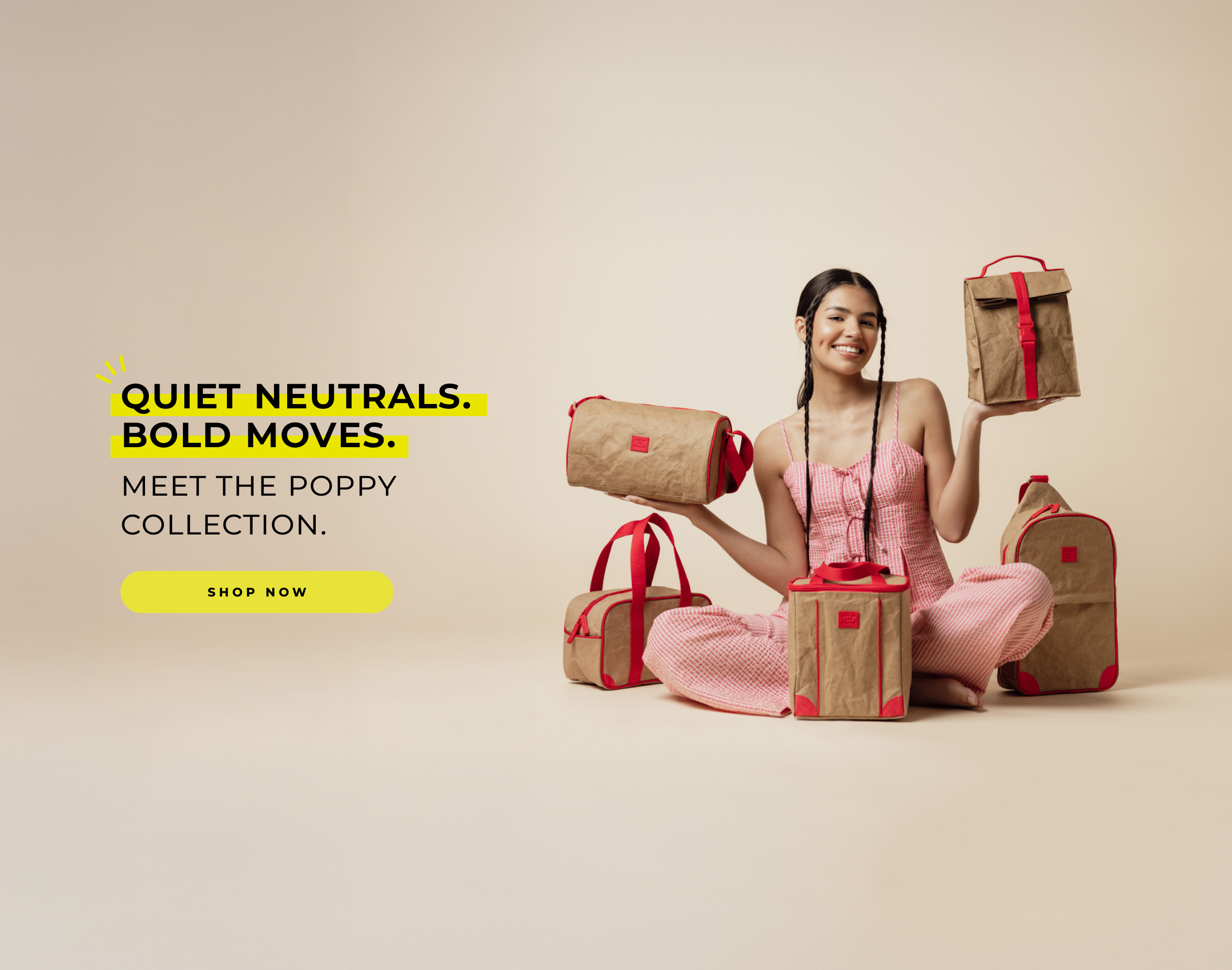 Woman in pink outfit posing with neutral-toned bags with red accents from the Poppy Collection on beige background