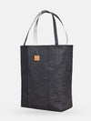 Black shopper tote bag with dual handles and small leather patch on neutral background