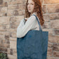 Girl holding a blue tote bag against a stone wall background