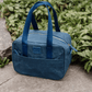 Navy blue lunch cooler bag on a concrete surface with greenery in the background