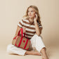 Woman sitting on floor holding On the Move Lunch Cooler with red handles and beige body against beige background