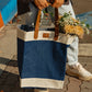 Jute Tall Tote in blue and natural colors with brown handles holding flowers, ideal for market trips and day excursions.