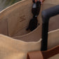 Interior pocket of Jute T-Strap Tote holding sunglasses with vegan leather handles and luggage strap visible.